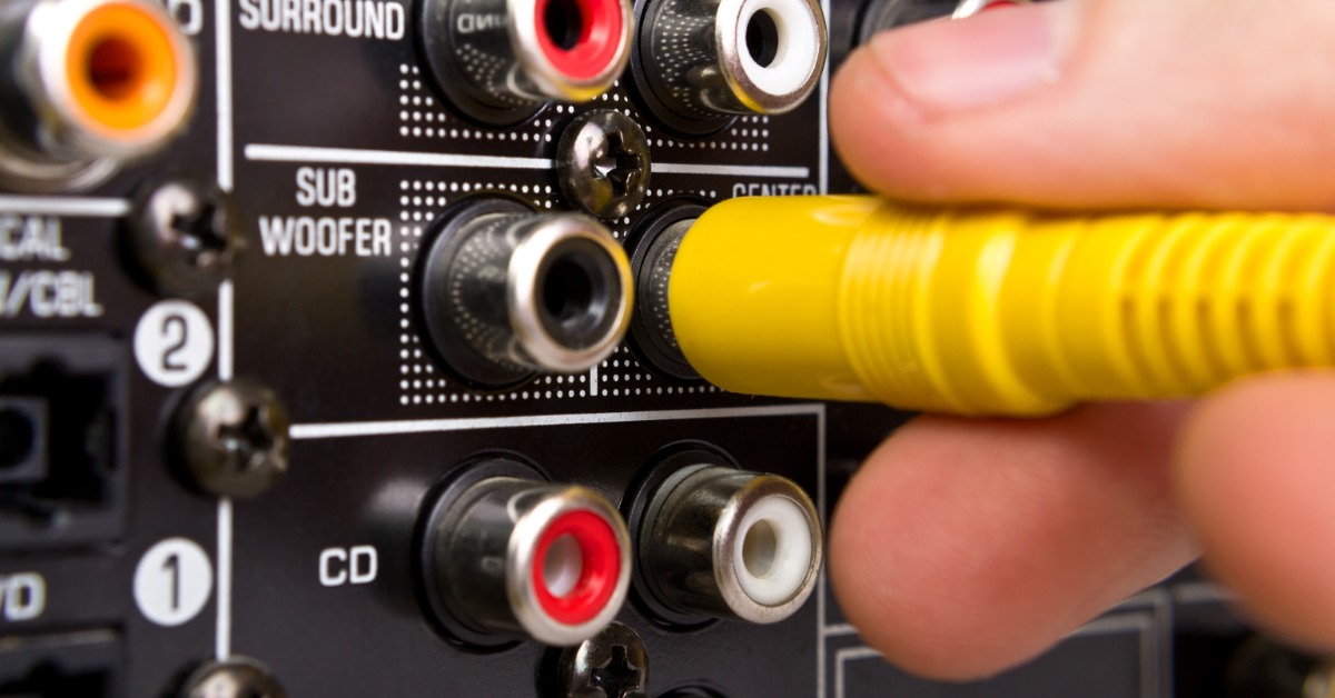 A person plugging in a yellow cable into a jack for the sound system. There are a bunch of jacks to plug into here.