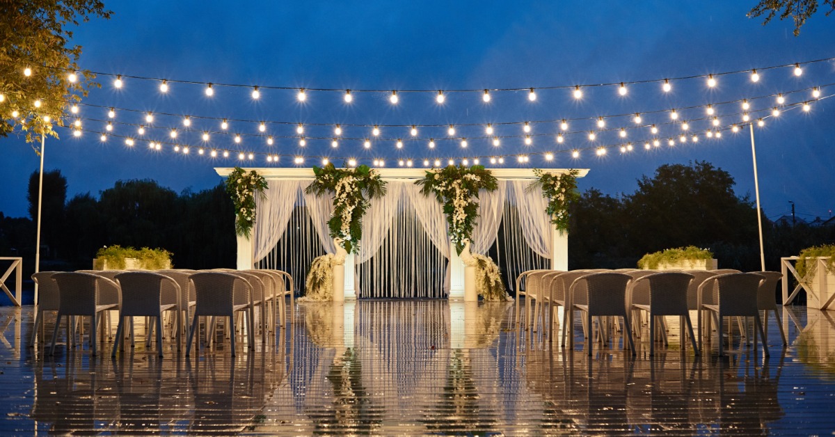 An outdoor wedding setup with many lights near the front and hanging overhead. The lights are reflecting off the ground.