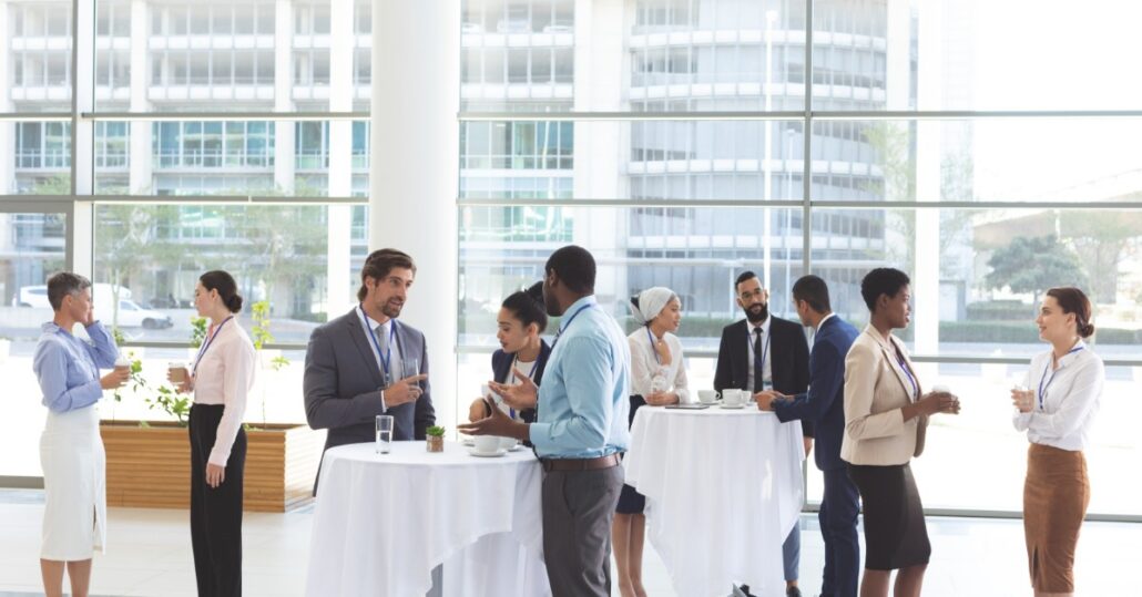 Business people are interacting in a common area, reviewing materials and speaking during a group discussion.