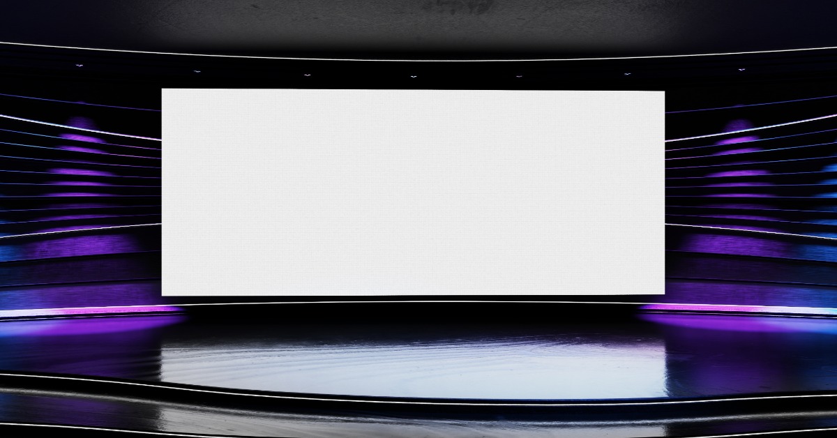 A room with a dark stage, a blank white screen, reflective flooring, and purple and blue side lighting.